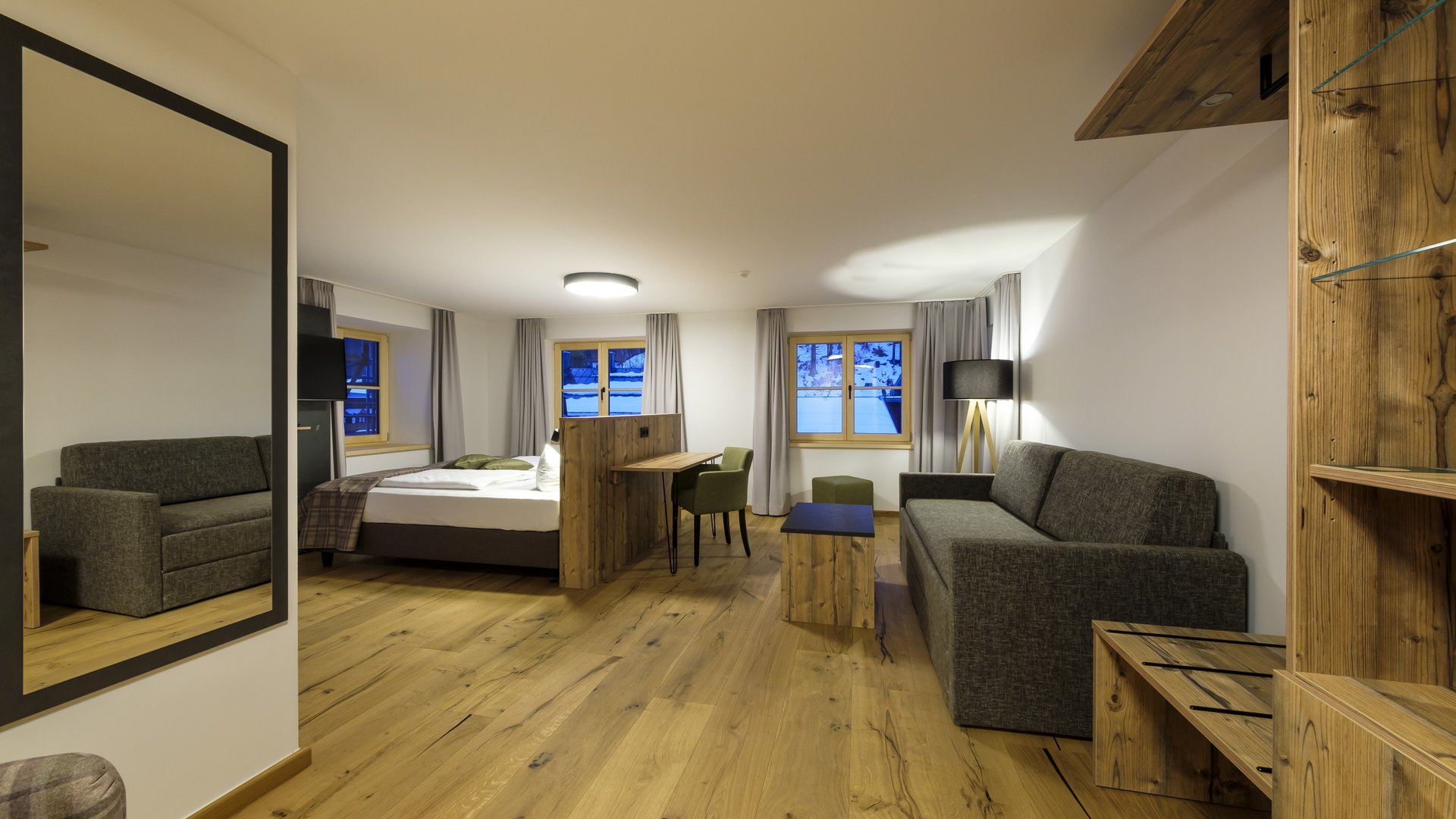 Wohlfühlen in der Unterkunft am Spitzingsee Modern eingerichtetes Hotelzimmer mit Holzmöbeln und zwei Sofas