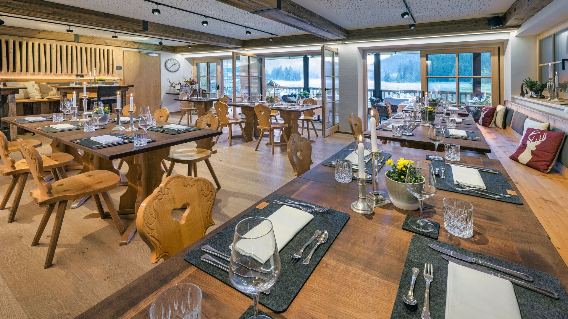 Gemütlich gedeckte Holztische in einem gut beleuchteten Restaurant mit Ausblick auf Berge