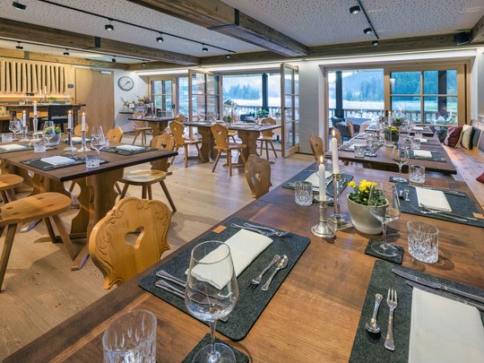 A hotel with sauna by the lake? Off to Alte Wurzhütte! Cozy set wooden tables in a well-lit restaurant with mountain view