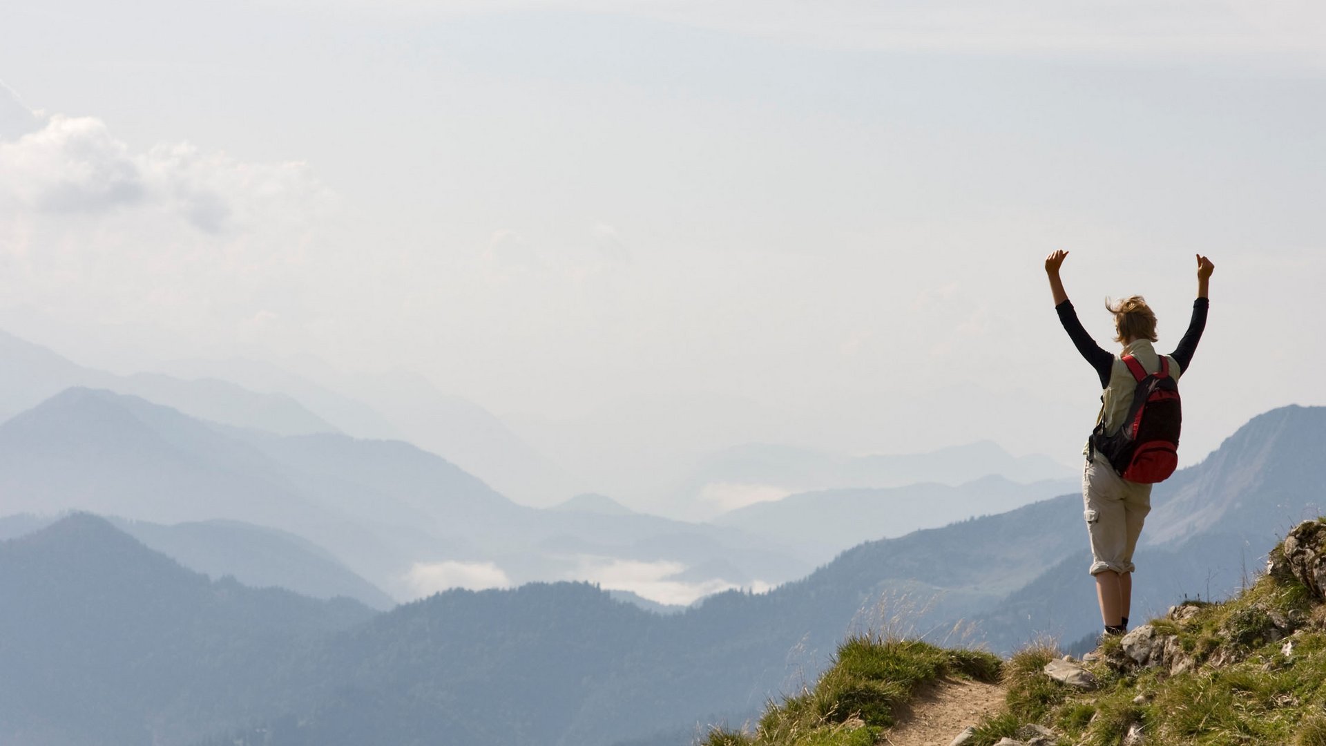 Wanderer mit Rucksack auf Berg mit Blick auf Nebel über Bergen und fliegendem Vogel