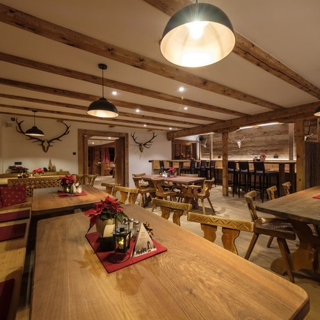 A look at Alte Wurzhütte Rustic tavern with wooden tables, chairs, and deer antlers on the wall
