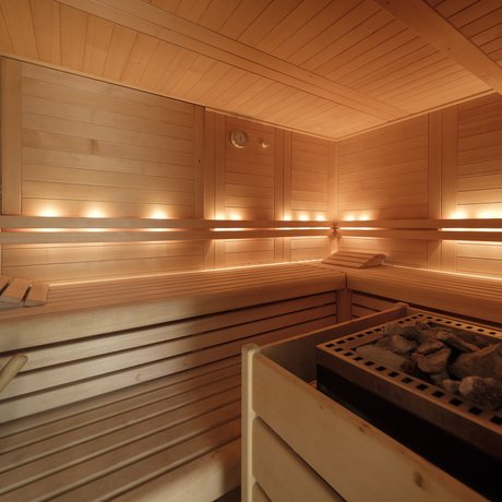 A look at Alte Wurzhütte Bright wooden sauna with stone heater and ambient lighting