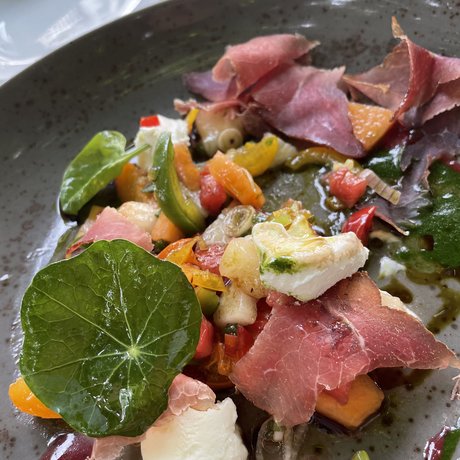 A look at Alte Wurzhütte Colorful appetizer with ham, vegetables, leafy greens, and cheese on gray plate