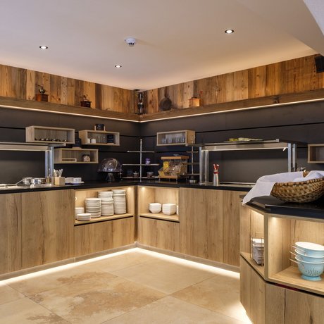 A look at Alte Wurzhütte Modern buffet with wooden cabinets, LED lighting, and kitchen utensils
