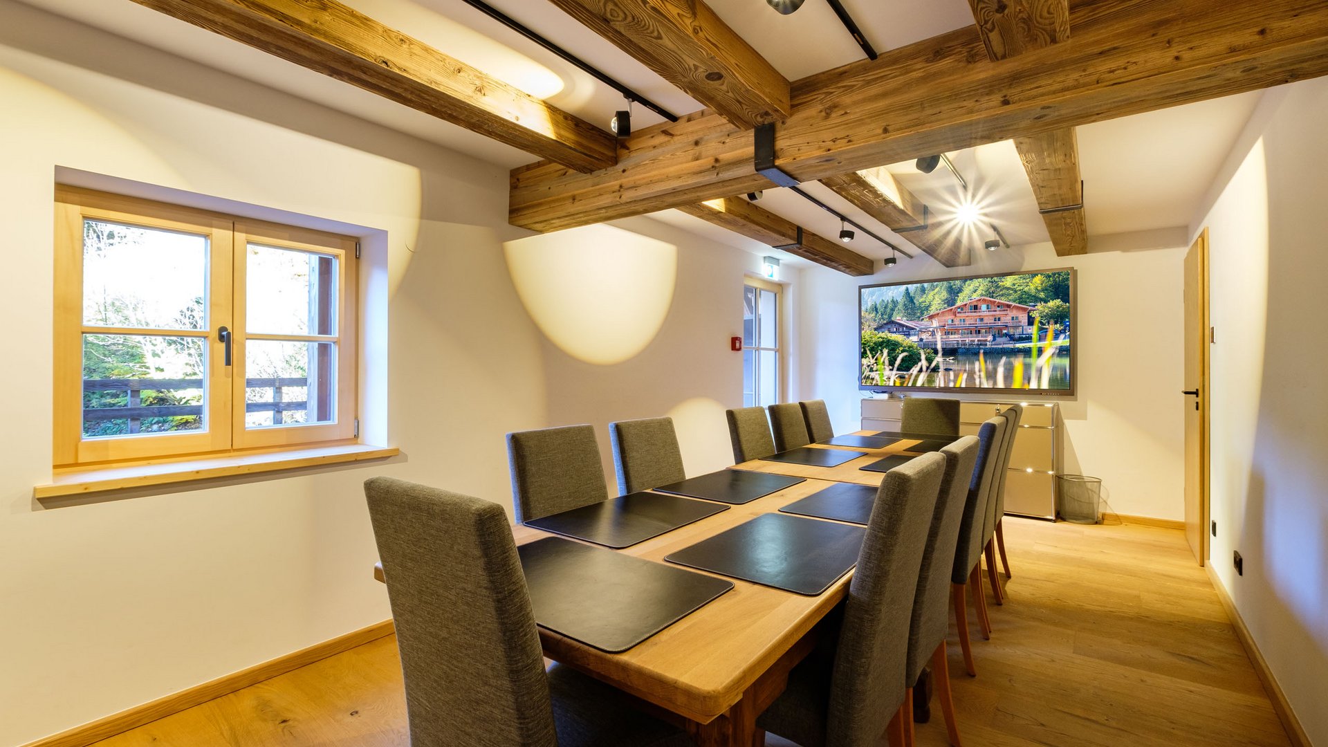 Konferenzraum mit langem Holztisch, grauen Stühlen und großen Fenstern
