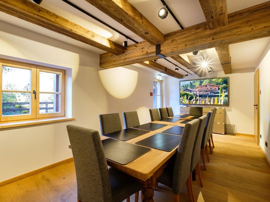 Conference rooms of our seminar hotel in Upper Bavaria Conference room with long wooden table, gray chairs, and large windows