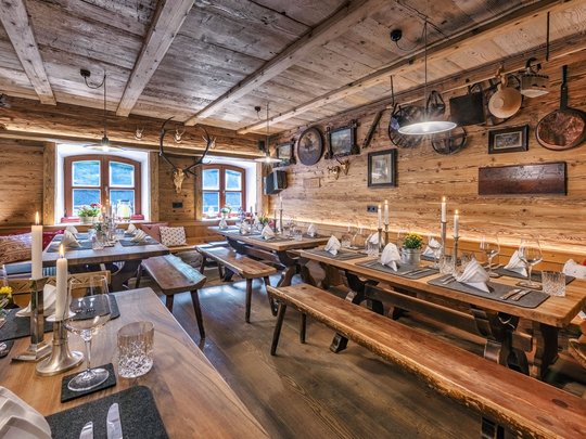 A hotel with sauna by the lake? Off to Alte Wurzhütte! Rustic alpine hut with wooden interior and tables set with candles