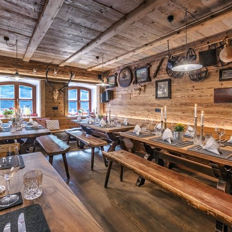 A look at Alte Wurzhütte Rustic alpine hut with wooden interior and tables set with candles