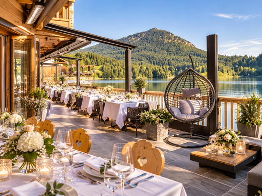Feiert eure Hochzeit am See! Restaurantterrasse mit gedeckten Tischen, Hängesessel und Blick auf See und Berge