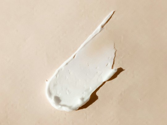 Massagen und Sauna am Spitzingsee Weiße Creme auf beige Hintergrund verteilt