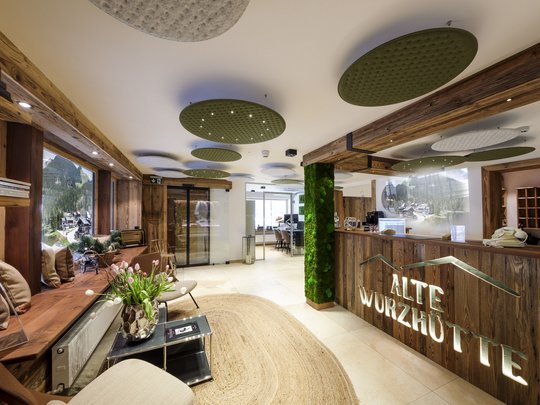 A hotel with sauna by the lake? Off to Alte Wurzhütte! Reception and lounge area of Alte Wurzhütte hotel with wooden accents and green decor