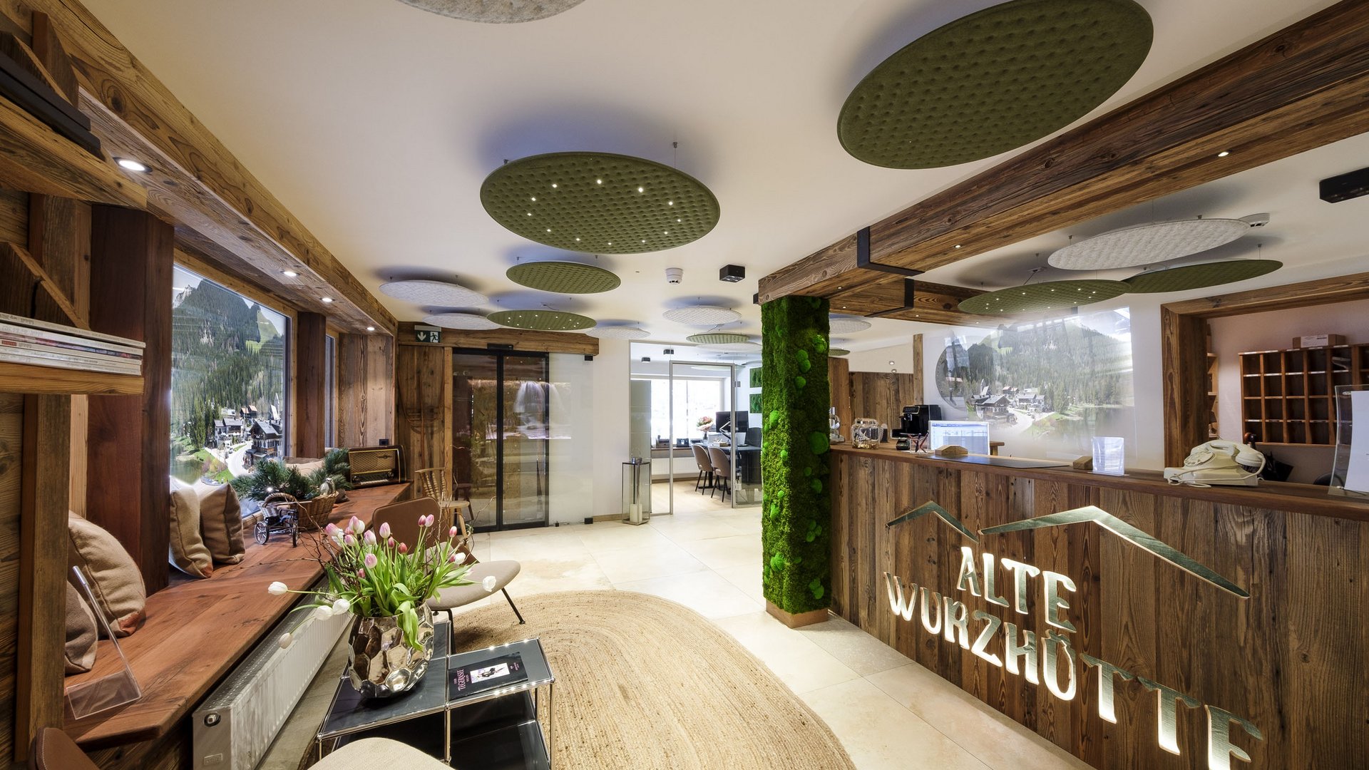 A hotel with sauna by the lake? Off to Alte Wurzhütte! Reception and lounge area of Alte Wurzhütte hotel with wooden accents and green decor