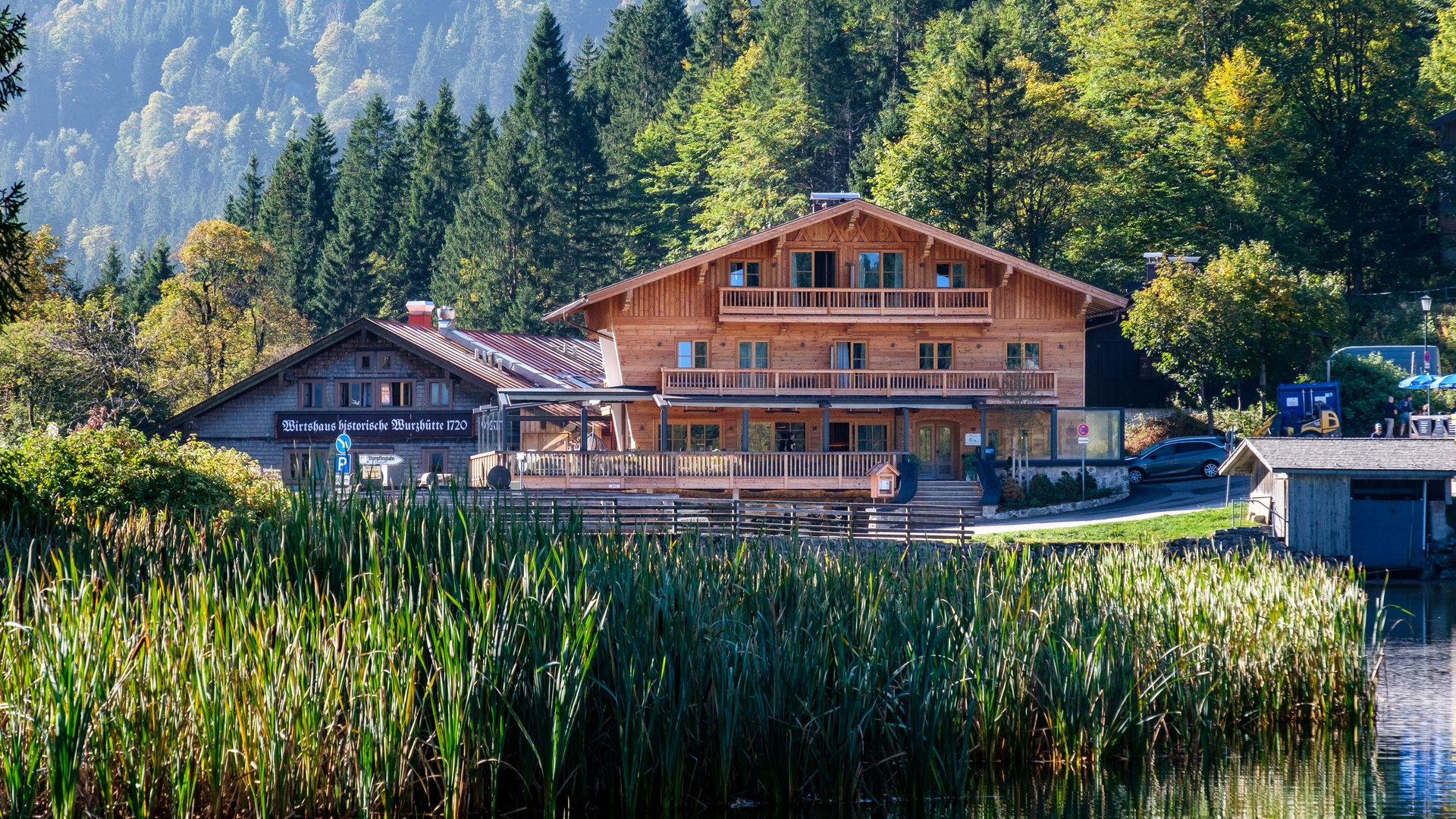 Holzhaus am See mit Bergen und Wald im Hintergrund