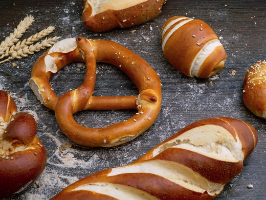 Welcome to our conference hotel in Upper Bavaria! Various pretzel breads on wooden surface with wheat stalks and flour