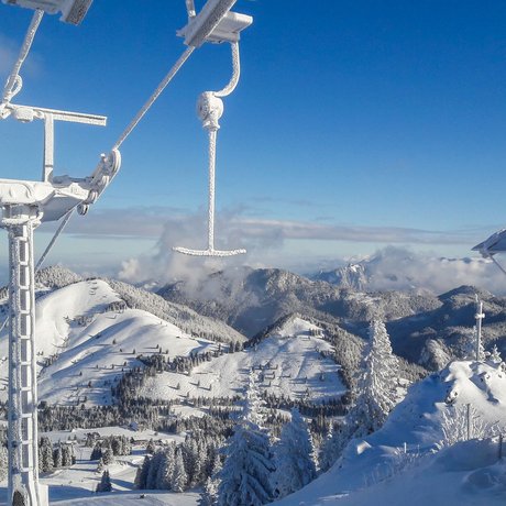 A look at Alte Wurzhütte Snow-covered ski area with chairlift and mountain landscape under clear sky