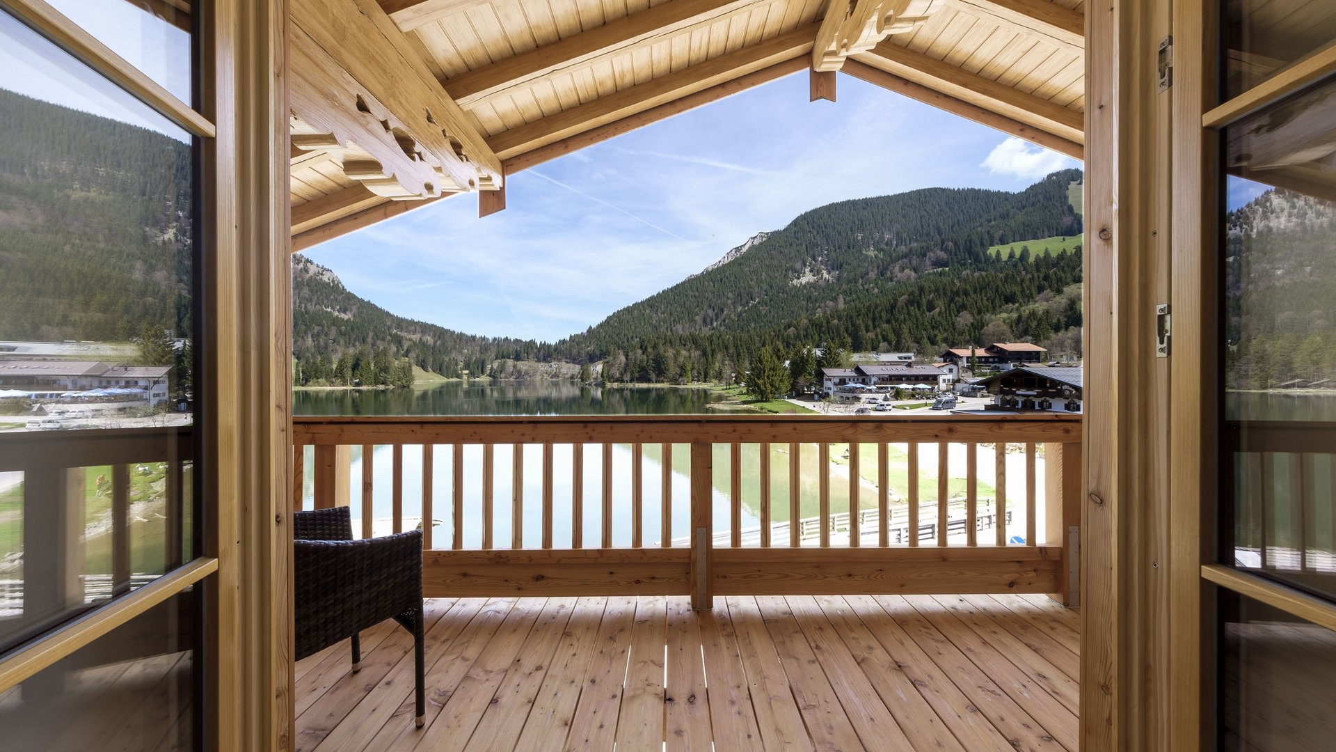 Blick von Holzveranda auf See und Berge unter blauem Himmel