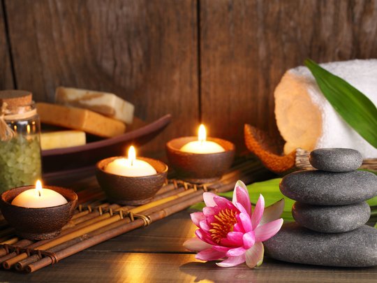 Massagen und Sauna am Spitzingsee Wellness-Set mit brennenden Kerzen, Seife, Steinen und Blume auf Holztisch