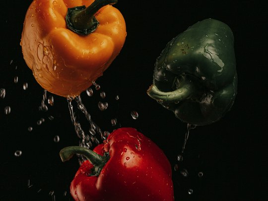 The perfect menu for your event Yellow, green, and red bell peppers with water droplets on black background