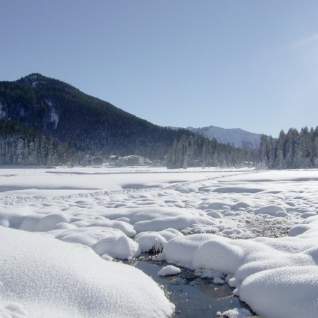 A look at Alte Wurzhütte Snow-covered landscape with mountains, houses, and blue sky under sunshine