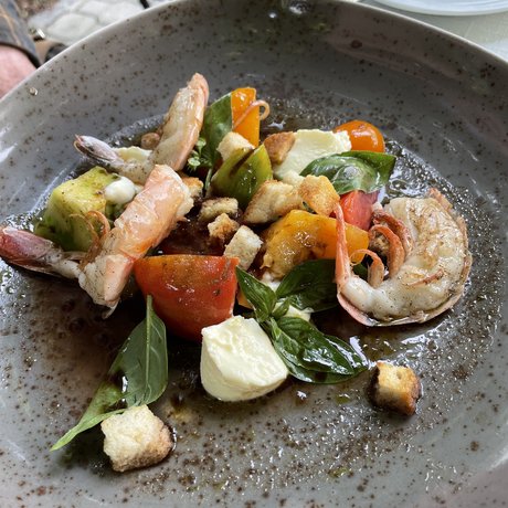 A look at Alte Wurzhütte Shrimp salad with tomatoes, mozzarella, basil, and croutons on a gray plate
