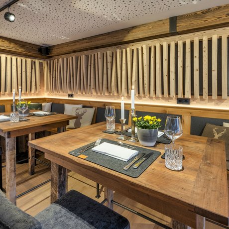 A look at Alte Wurzhütte Cozy rustic dining area with wooden tables and decorative deer motif cushions
