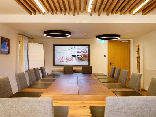 Conference rooms of our seminar hotel in Upper Bavaria Modern conference room with large wooden table and presentation screen