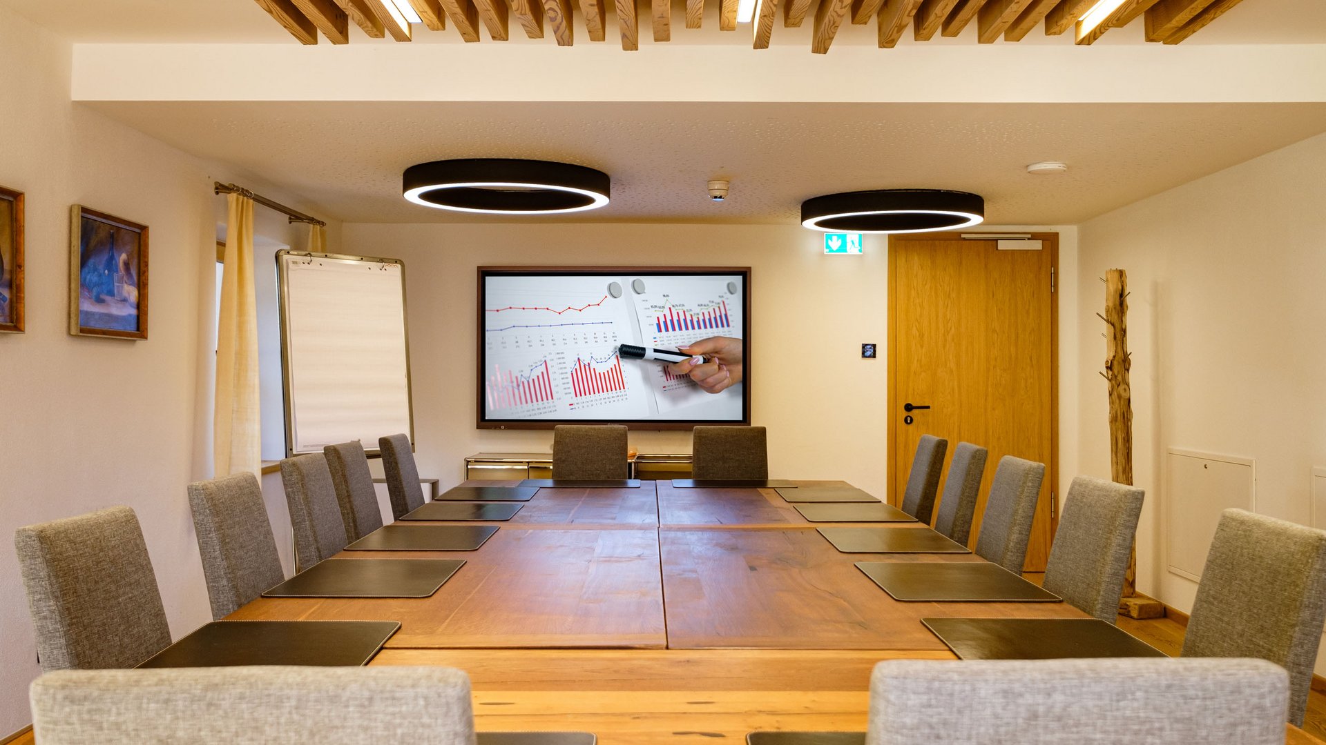 Modern conference room with large wooden table and presentation screen