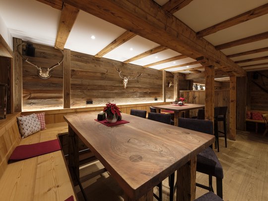 A hotel with sauna by the lake? Off to Alte Wurzhütte! Rustic dining room with wooden tables, benches, and antler decorations on the wall
