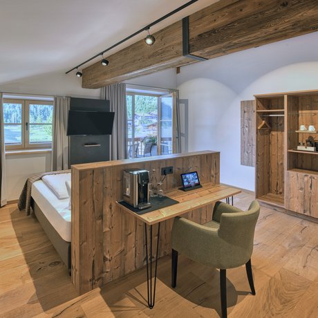 A look at Alte Wurzhütte Bright hotel room with wooden accents, desk, armchair, and balcony view